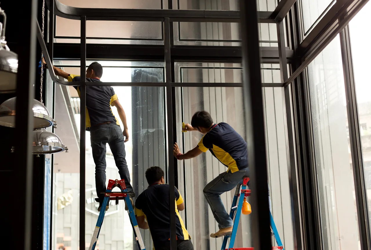 Three installers working together on tall windows, with two on ladders.